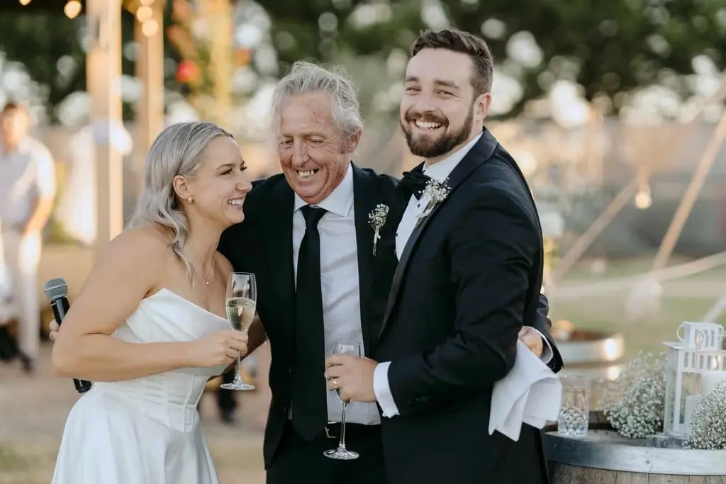 Newlyweds laughing with an older guest at the reception