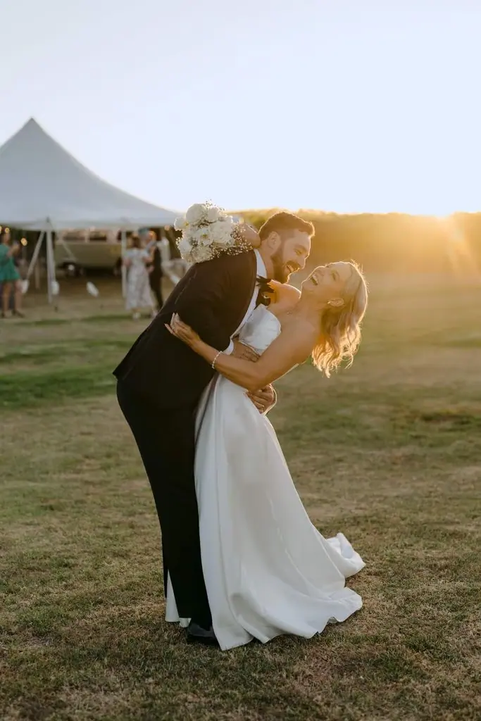 Groom kissing the bride's forehead in warm sunset light