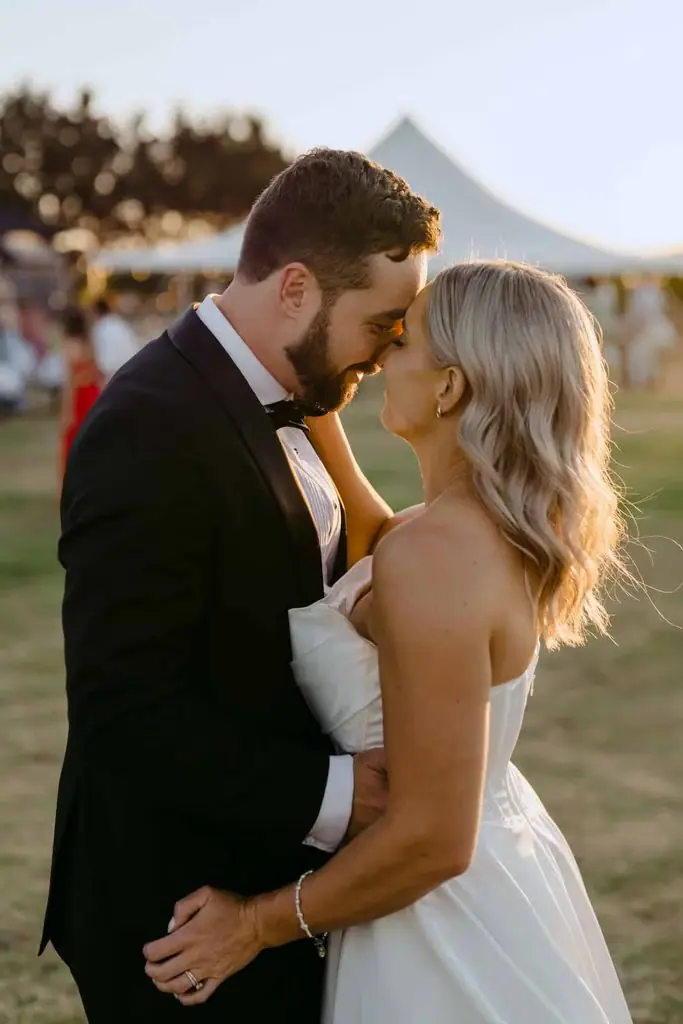 Newlyweds smiling at each other in a field