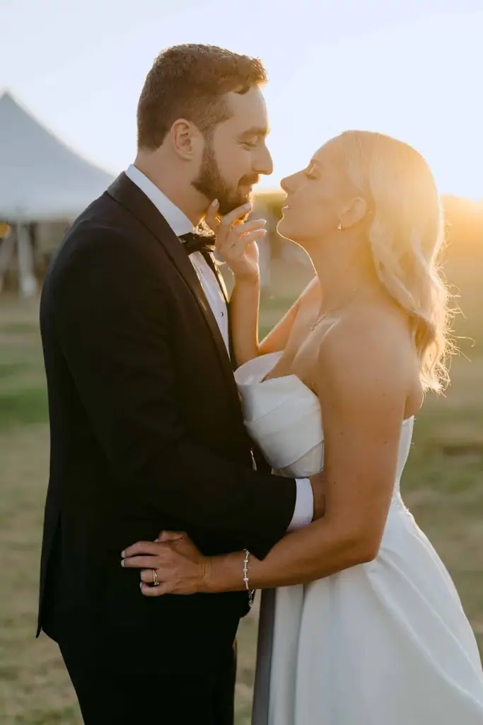 Groom kissing the bride's forehead in sunset light