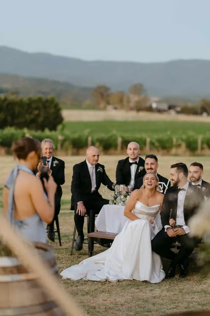 Newlyweds laughing from their seats beside the vineyard