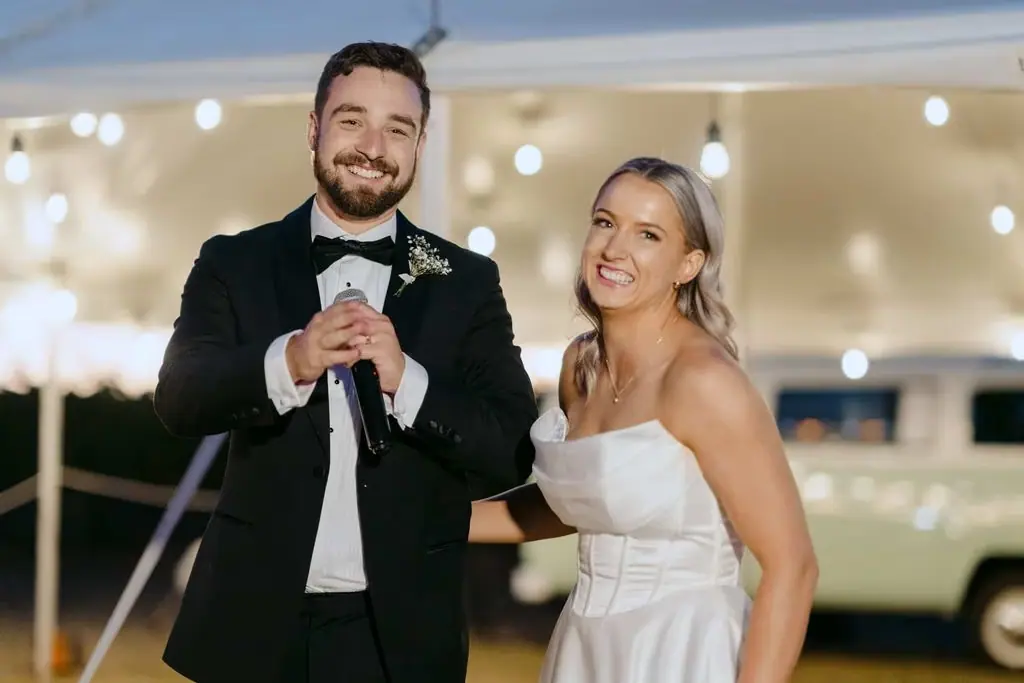 Groom speaking into a microphone with the bride beside him