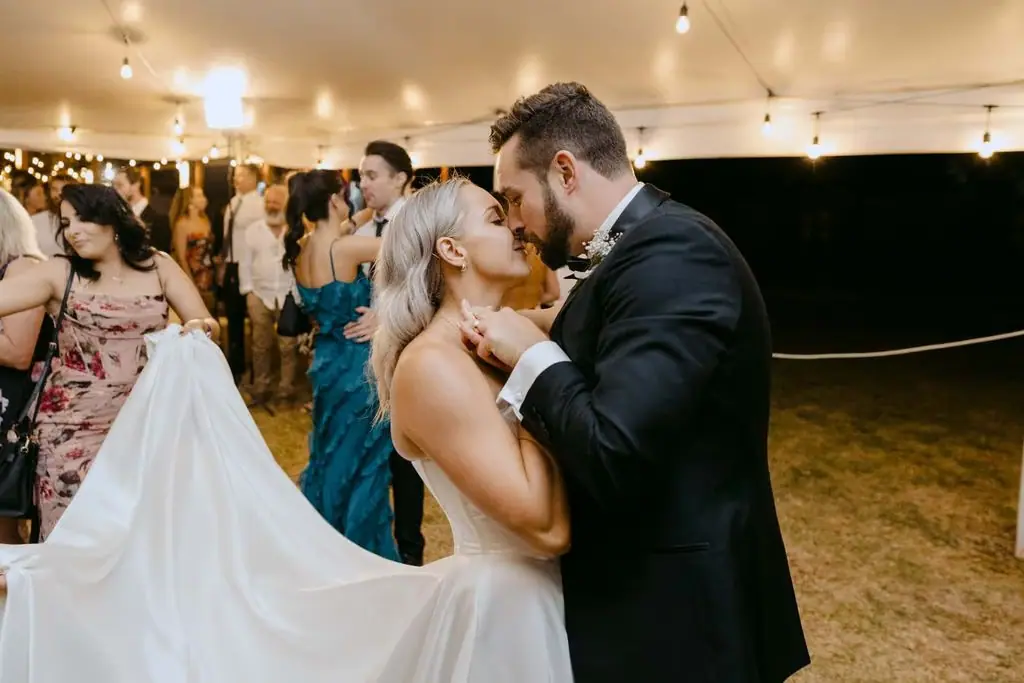 Couple kissing on the dance floor beneath the marquee