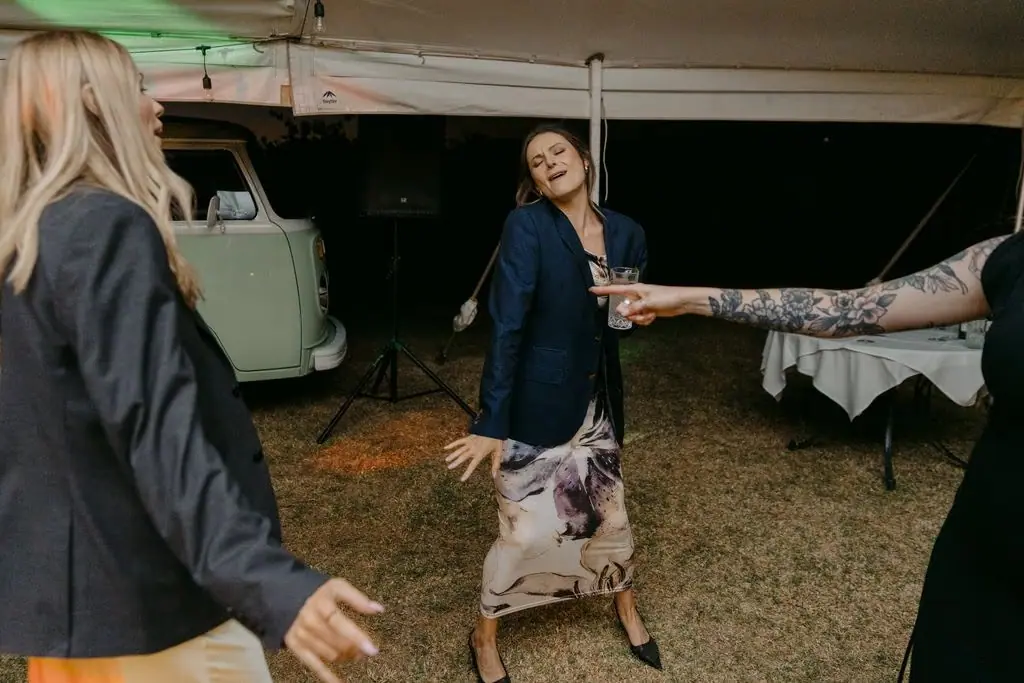 Guests holding hands and dancing together beneath the marquee