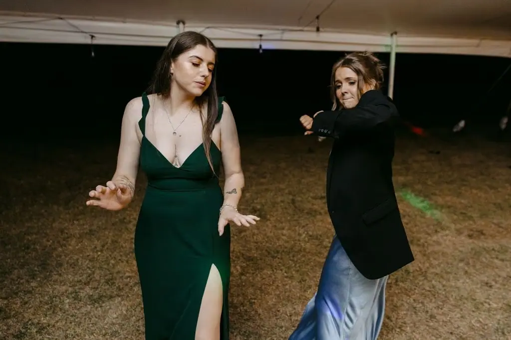Two guests dancing together beneath coloured party lights