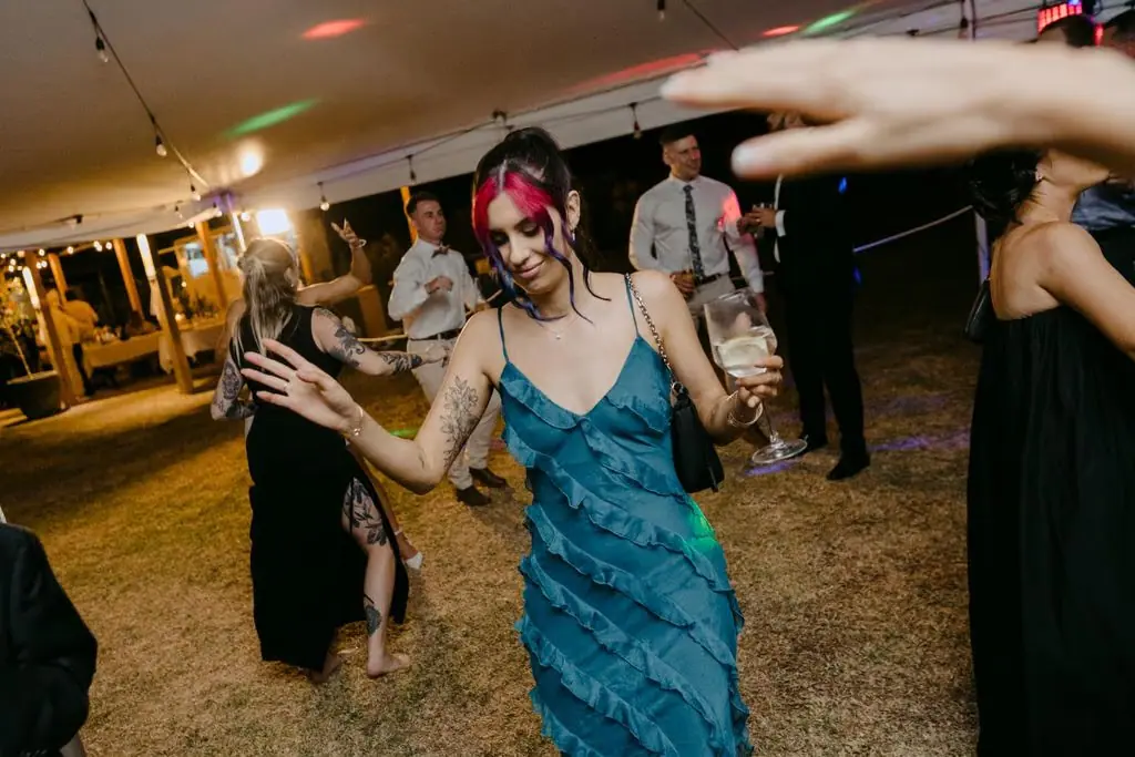 Guest dancing with a drink beneath the marquee