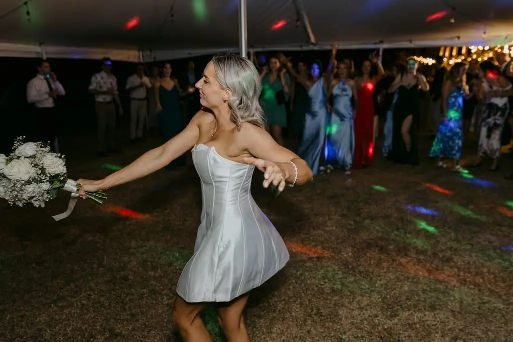 Bride dancing and holding her bouquet after dark