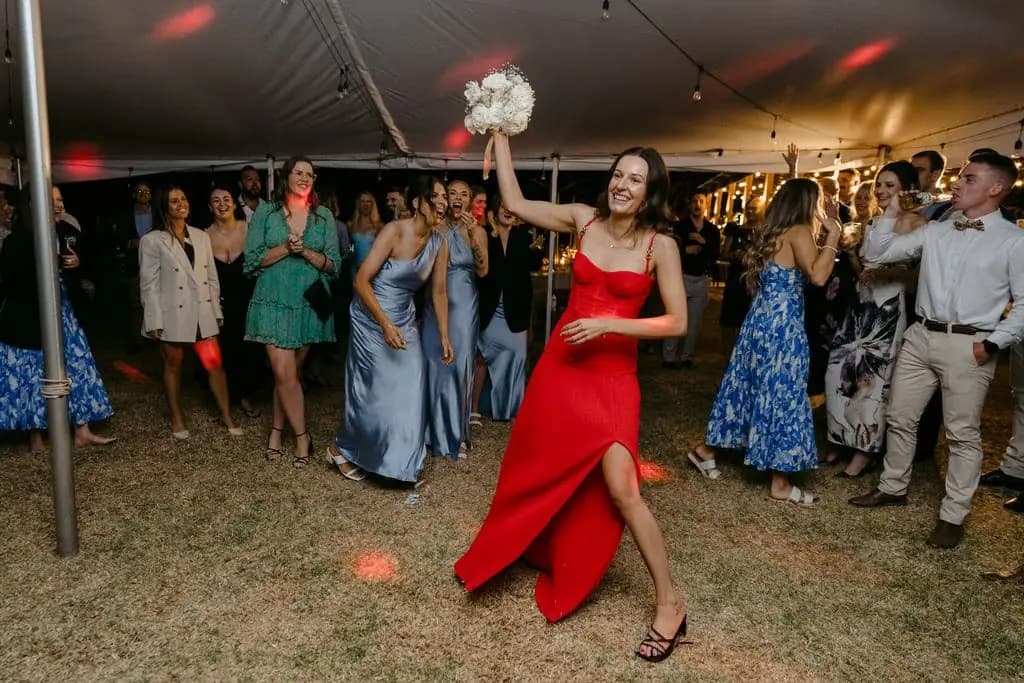 Guest in a red outfit raising a bouquet on the dance floor