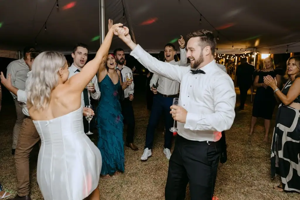 Bride raising her hand towards a guest on the dance floor
