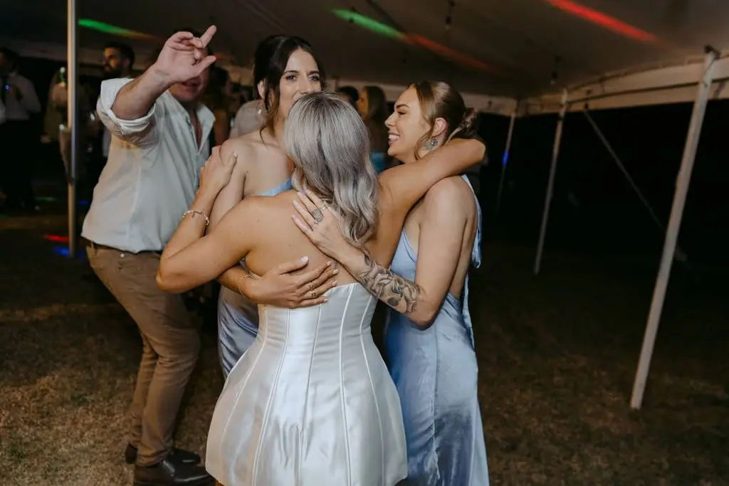 Bride and bridesmaids embracing on the dance floor
