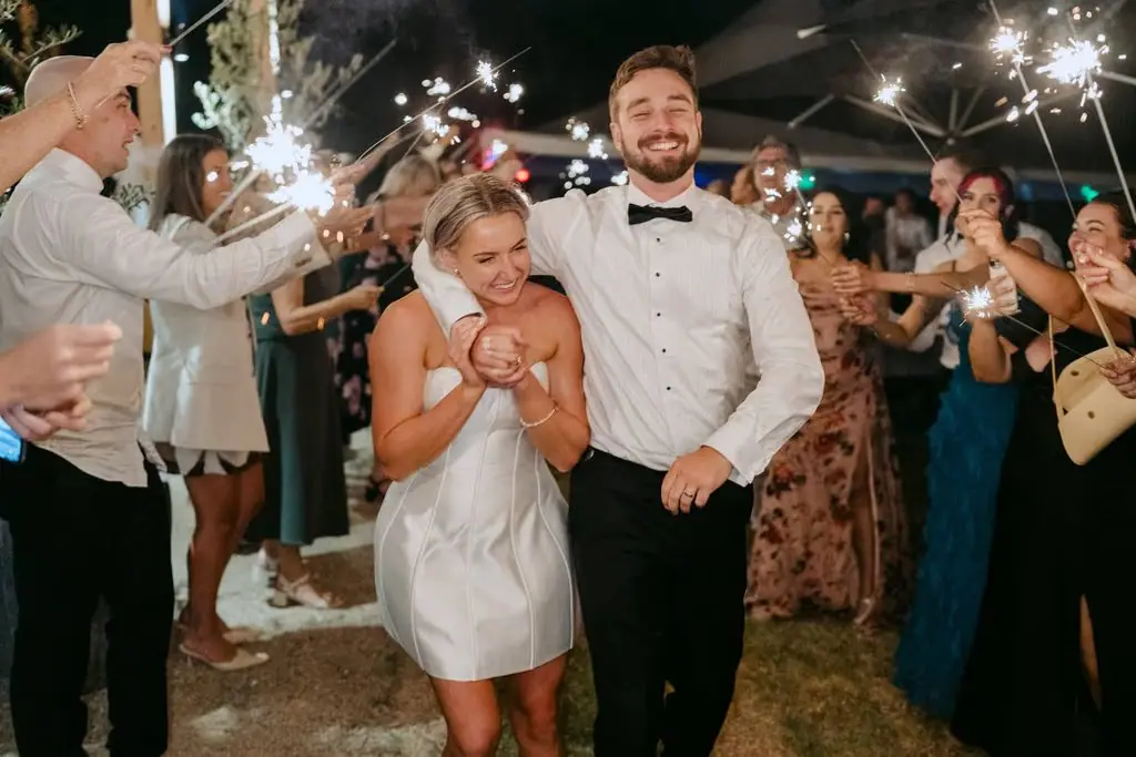 Newlyweds smiling as they walk through a sparkler farewell