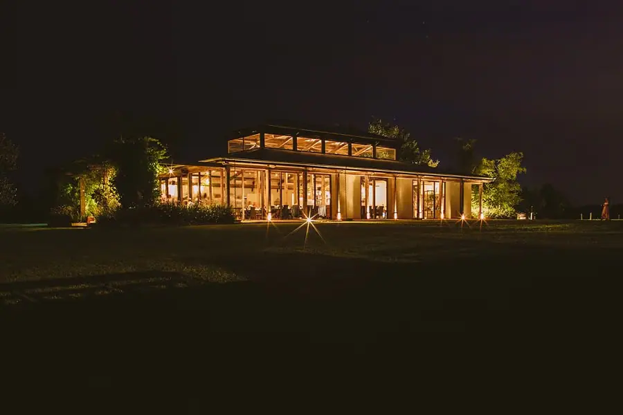 Warmly illuminated reception building surrounded by a dark lawn at night.