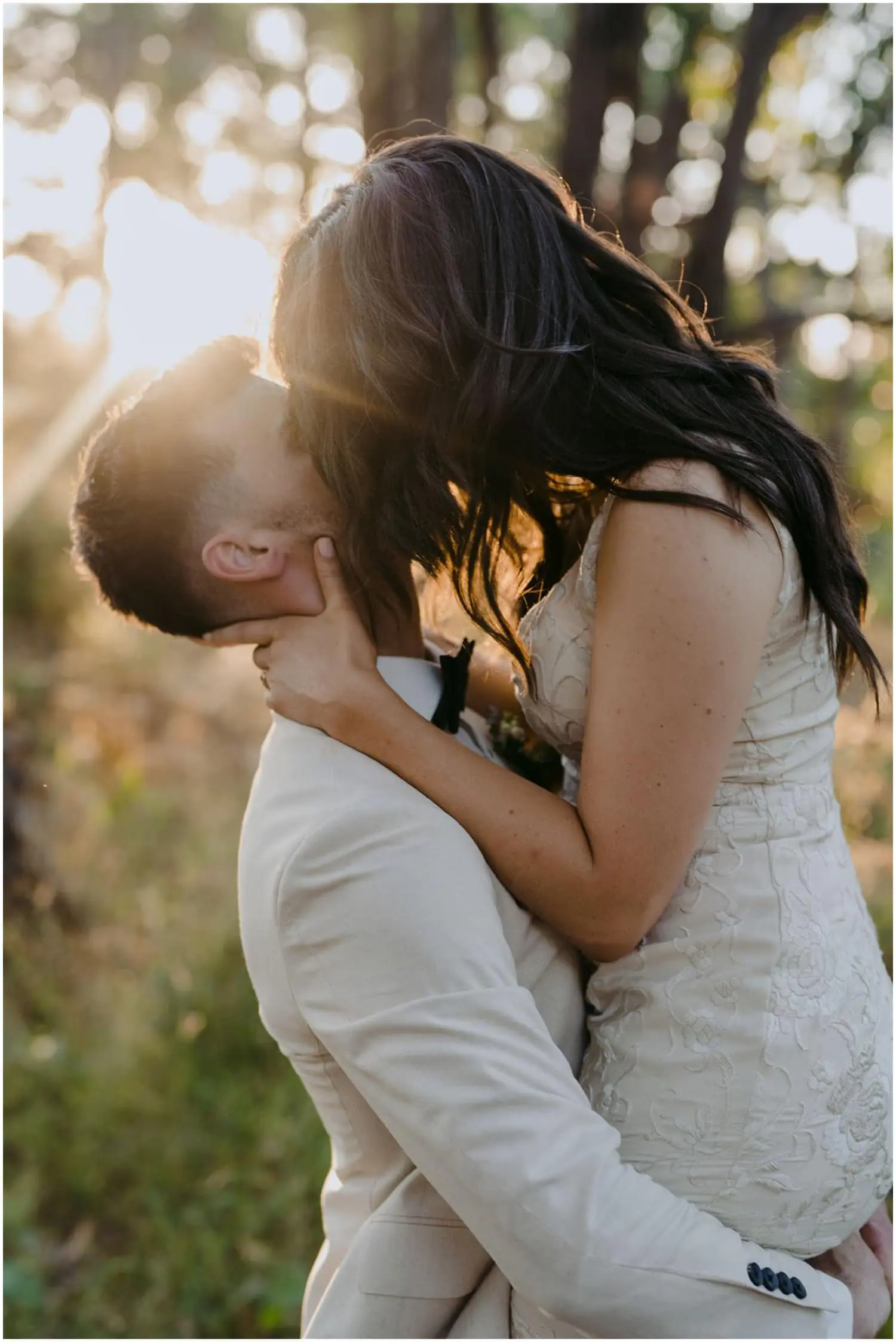 Groom lifting the bride as they share a kiss in a garden.