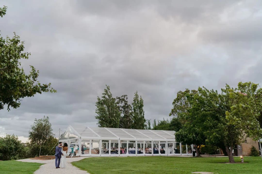 Clear marquee on a lawn beneath a grey cloudy sky.