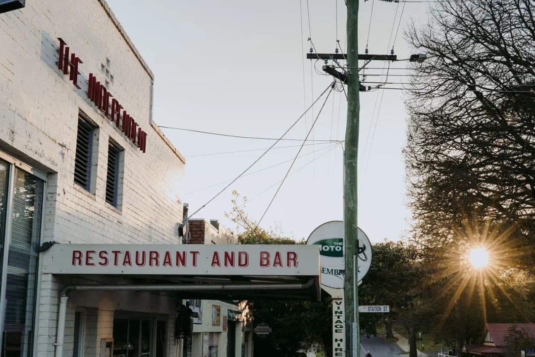 White restaurant building and roadside sign in low evening sunlight.