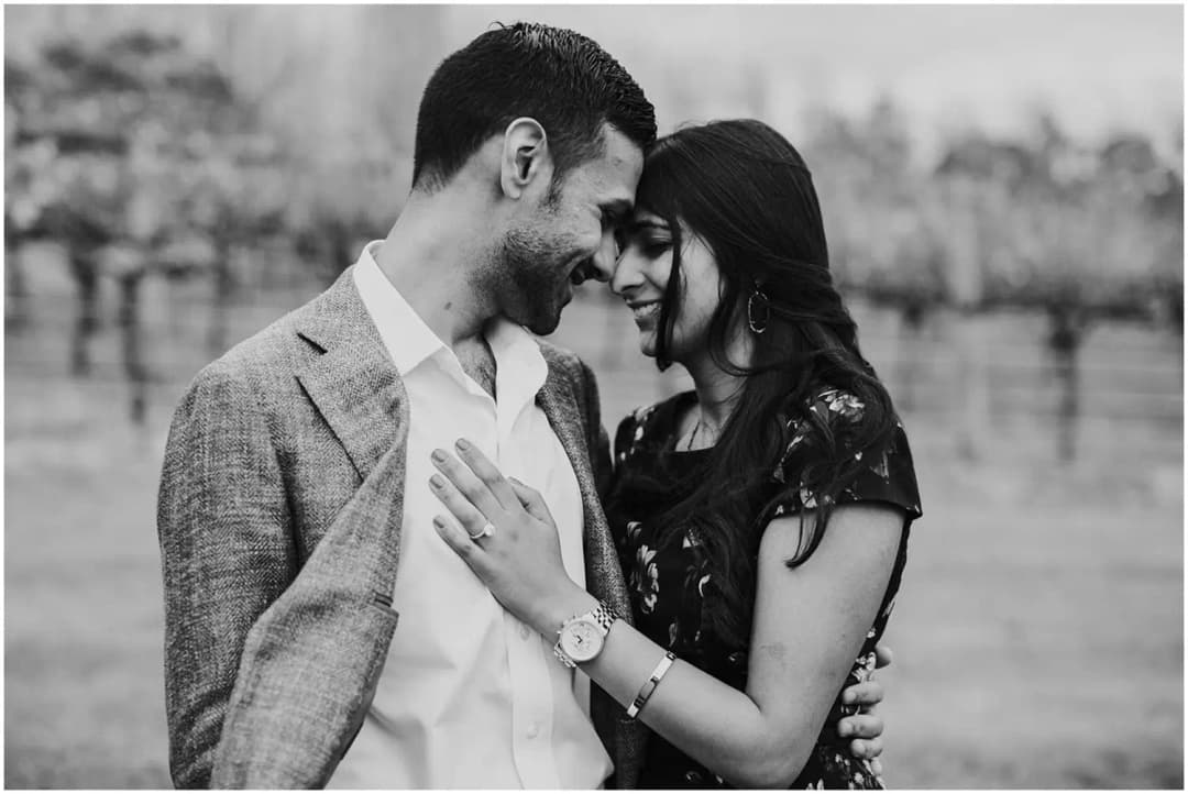 Black-and-white portrait of a couple leaning their foreheads together.