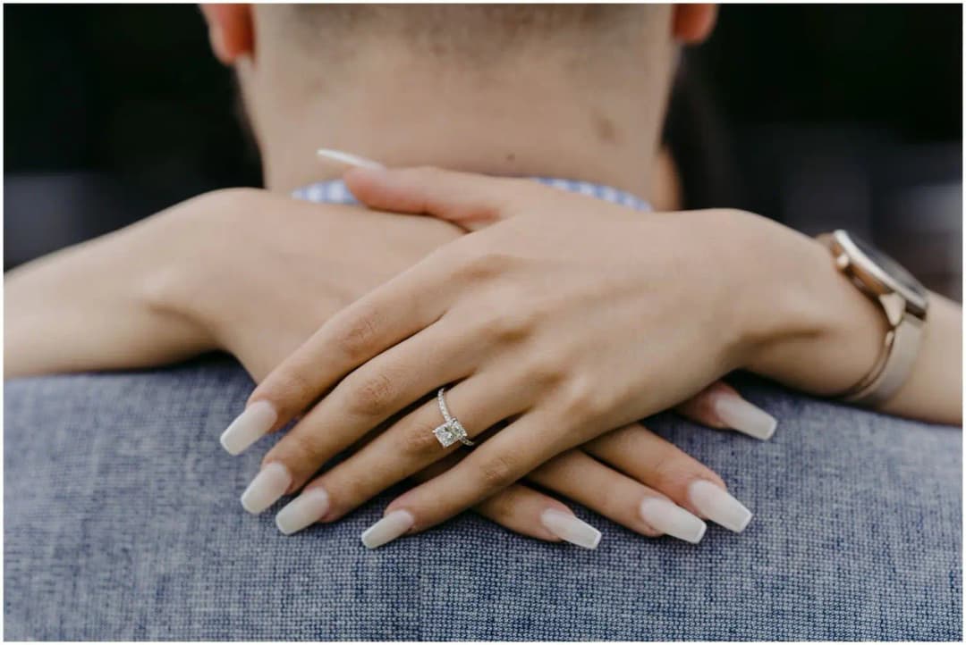 Close-up of a woman's ring as she embraces a man's shoulders.
