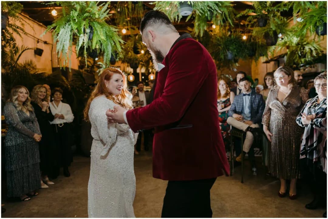 Bride and groom holding hands on the dance floor while guests watch