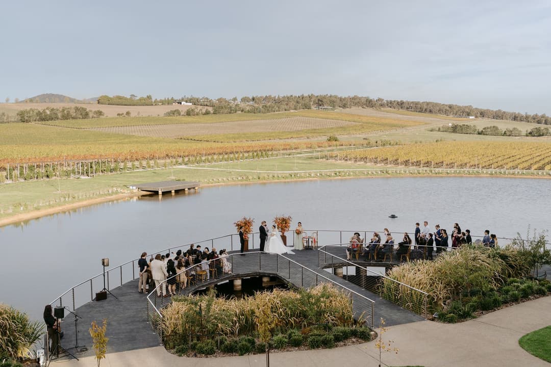 Guests gathered on a lakeside terrace overlooking vineyard hills.